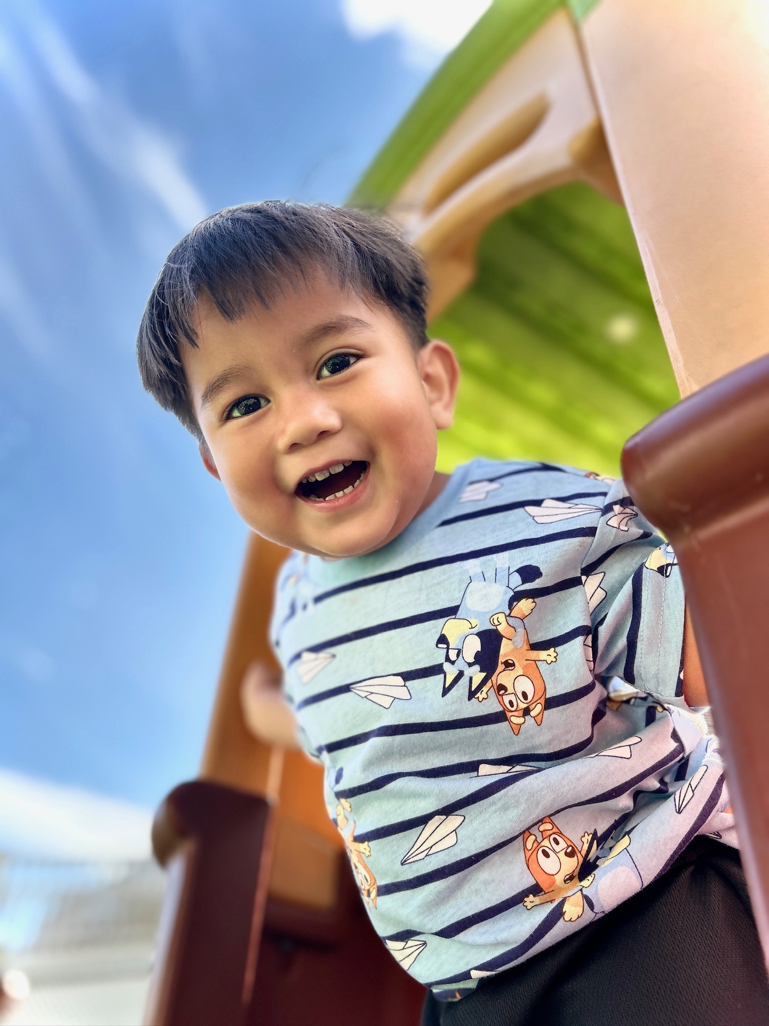 Boy in Bluey shirt smiling on playground