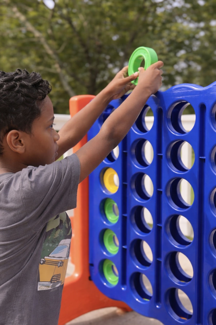 Child playing giant Connect 4 at camp