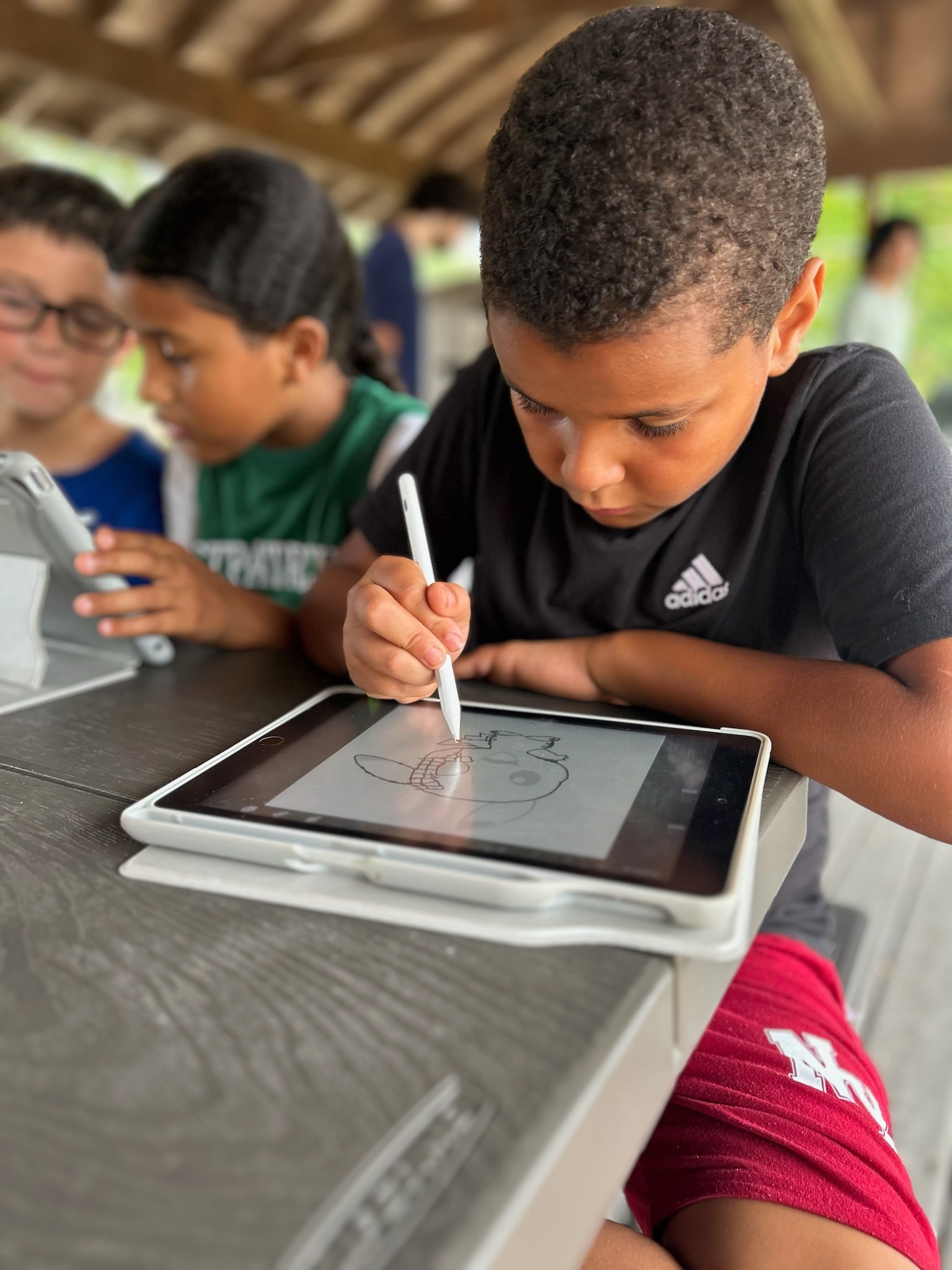Children drawing on iPads at camp