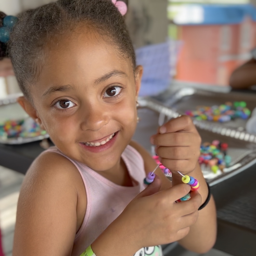 Girl making beaded jewelry at camp