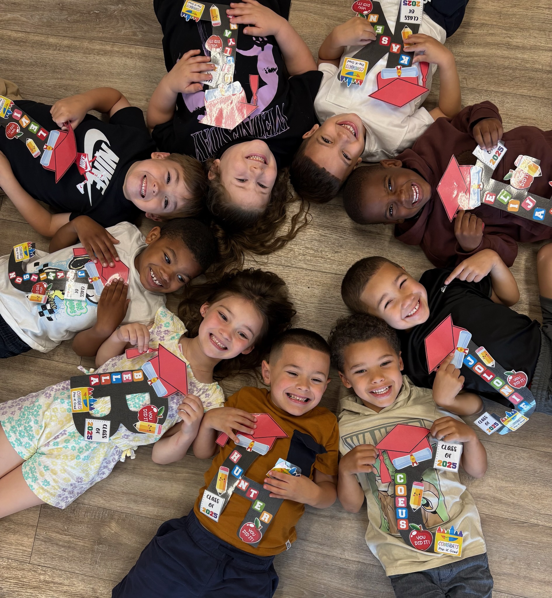 Pre-K graduates lying in a circle with Class of 2025 crafts