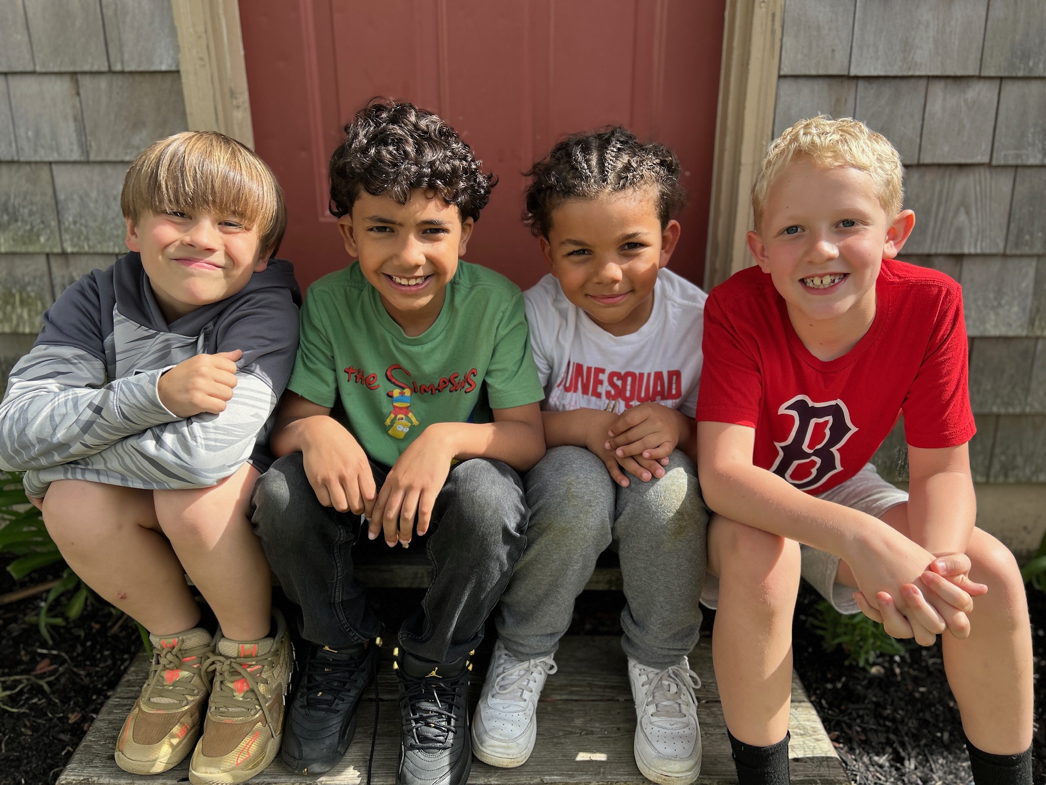 Four school-age friends sitting together on the porch