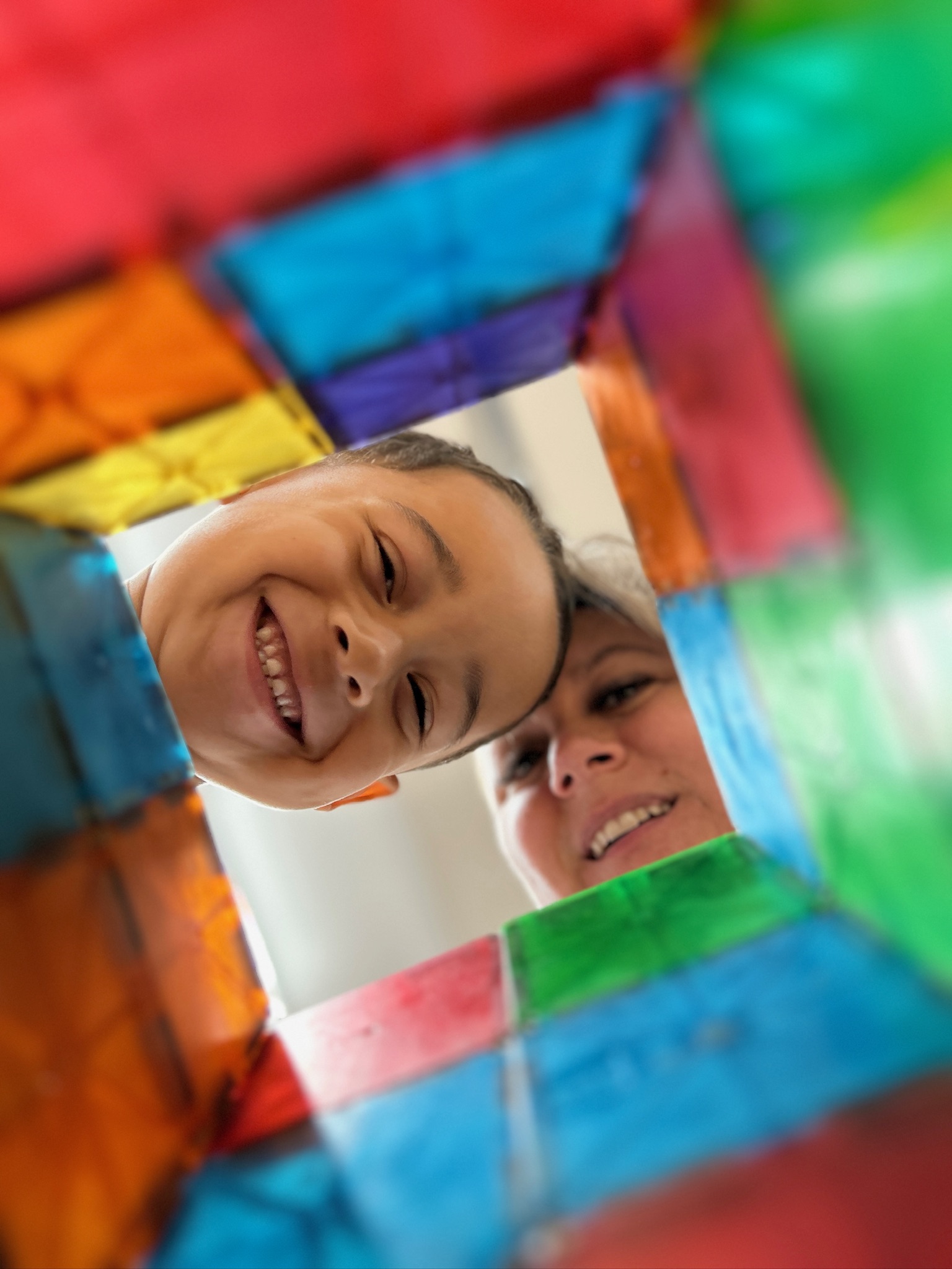 Child and teacher peeking through colorful magnetic tiles