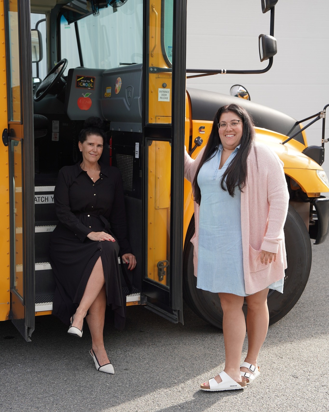 Karen Rogers and Alicia Bettencourt, LPC Transportation Co-Directors, in front of a school bus