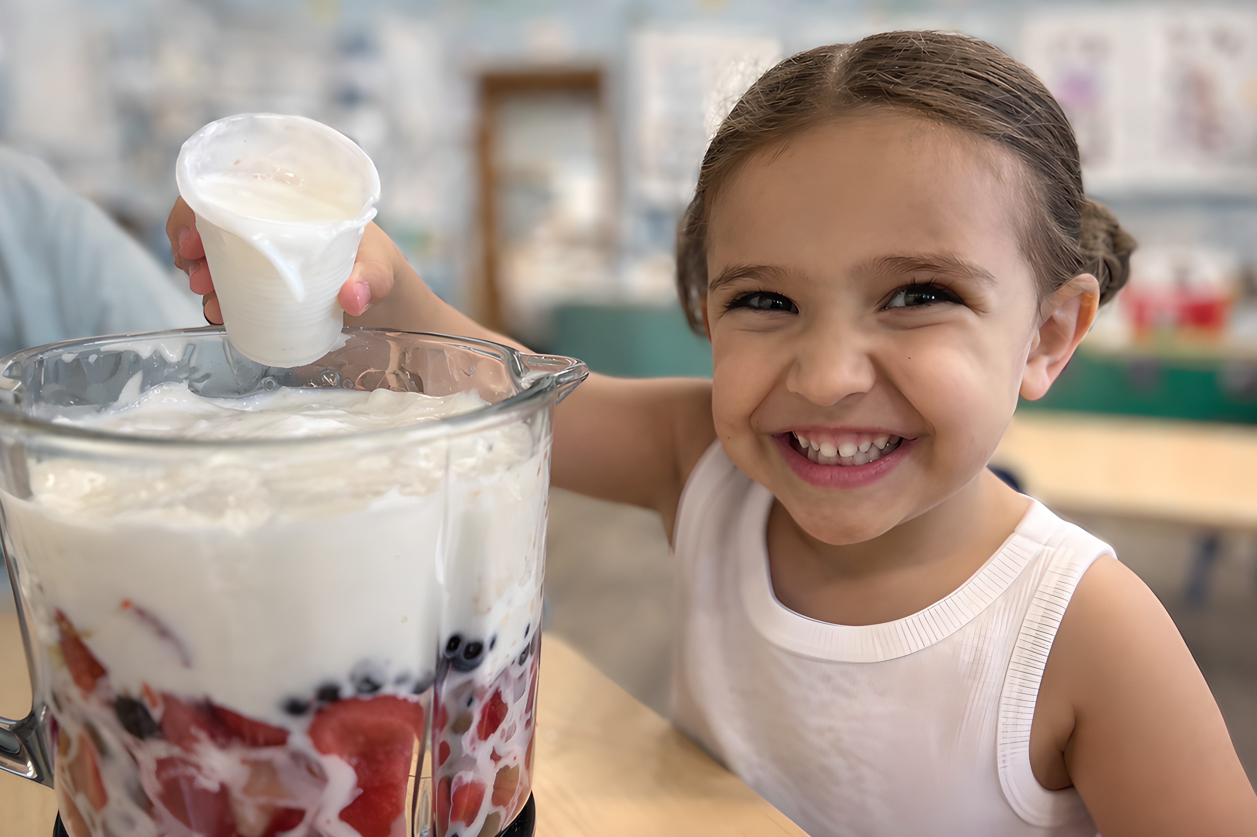 Child helping prepare a healthy fruit smoothie at Little People's College